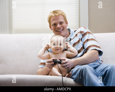 Uomo e bambino sul divano con video controller di gioco sorridente Foto Stock
