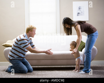 Uomo in ginocchio e donna insegnare al bambino a piedi Foto Stock