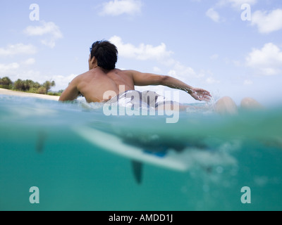 Uomo disteso sulla tavola da surf in acqua Foto Stock