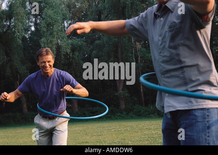 Gli uomini utilizzano Hula Hoops all'aperto Foto Stock