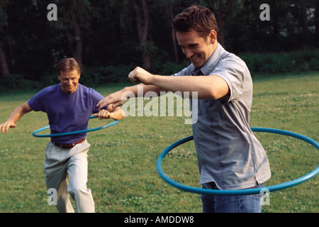 Gli uomini utilizzano Hula Hoops all'aperto Foto Stock