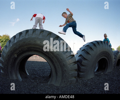 Bambini che giocano su grandi pneumatici nel parco giochi Foto Stock