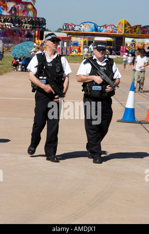 Polizia armata di pattuglia a un air show luna park in background Foto Stock