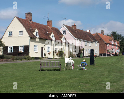 Monaci Eleigh villaggio verde casa cottage indietro vista persone rilassante artista & cavalletto al lavoro storico vecchia pompa d'acqua Suffolk East Anglia Inghilterra Regno Unito Foto Stock