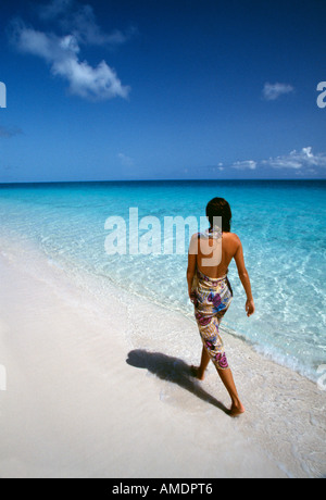 Turks e Caicos Provo donna cammina lungo la spiaggia in pareo Foto Stock