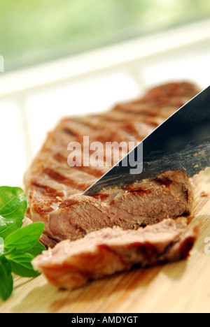 Bistecca alla griglia essendo tagliato su un tagliere Foto Stock