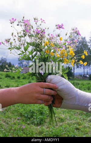 Ragazzo con mano nel cast dando bouquet di fiori selvaggi alla ragazza per la festa di mezza estate in Svezia Foto Stock