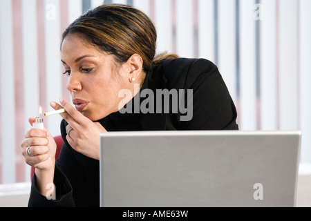 Vista di una donna d'affari di fumare in ufficio. Foto Stock