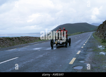 Elderrly giovane alla guida di una annata aperto auto lungo il Ring of Kerry in Irlanda sotto la pioggia battente Foto Stock