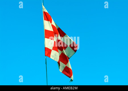 Il bianco e il rosso bandiera a scacchi battenti contro un cielo blu Foto Stock