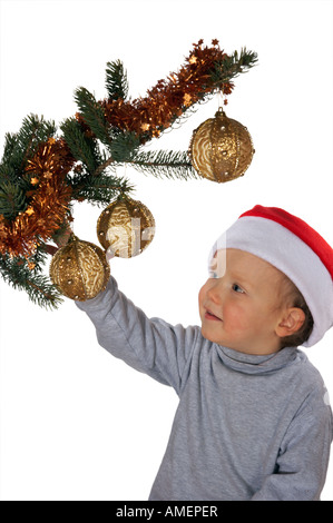 Piccolo Ragazzo giocoso sotto l albero di Natale ramo su sfondo chiaro non isolato Foto Stock