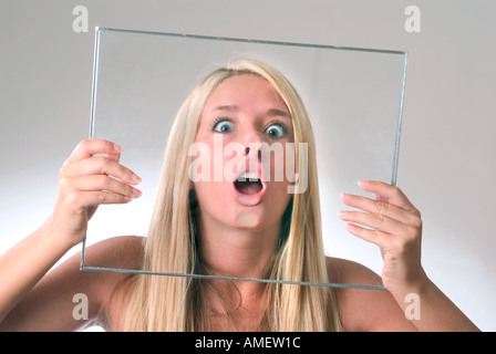 Giovane donna con il volto schiacciato contro il vetro Foto Stock