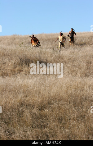 Tre Native American Indian uomini in esecuzione in discesa in morti erbe del Dakota del Sud Foto Stock