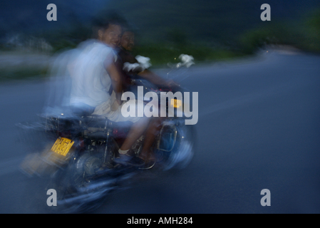 Cina Guangxi vicino a Yangshuo velocizzando motociclisti in sella al tramonto su una strada di campagna Foto Stock