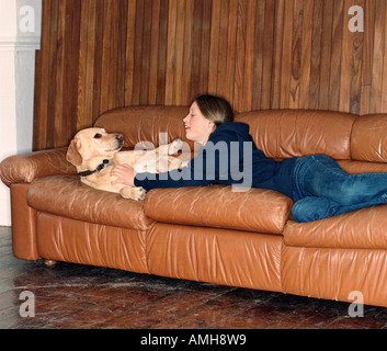 Ragazza adolescente sdraiato sul divano con il cane Foto Stock