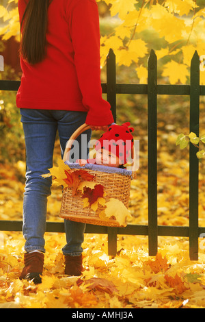 Madre bambino portando in cesto in mezzo a colori dell'autunno Foto Stock