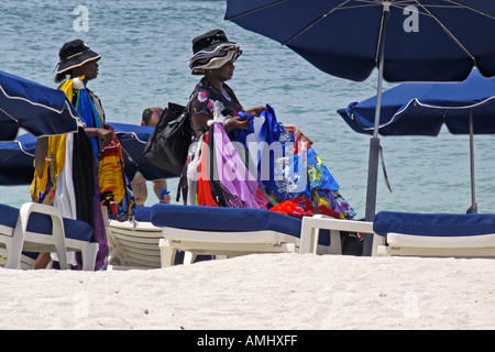 Le donne la vendita di cappelli e asciugamani da spiaggia a piedi tra lettini grande spiaggia della Baia di Philipsburg St Maarten Foto Stock