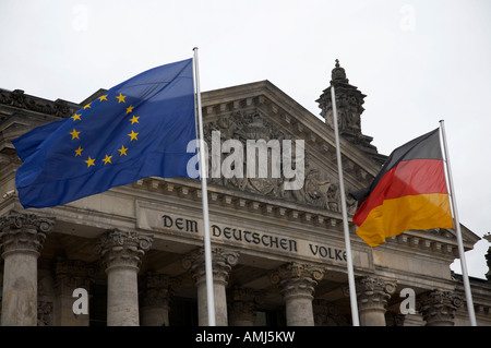 Unione europea e bandiera tedesca battenti svolazzanti sui pennoni al di fuori del Reichstag a Berlino Germania Foto Stock