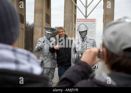 Turista che posano per una fotografia con verniciato argento street intrattenitore vestito come est guardia tedesco Porta di Brandeburgo a Berlino Foto Stock