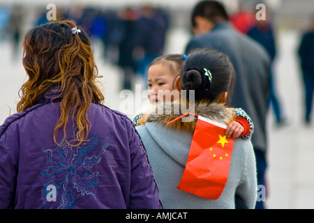 Giovane ragazza cinese e sua madre con bandiera nazionale Piazza Tiananmen Pechino CINA Foto Stock