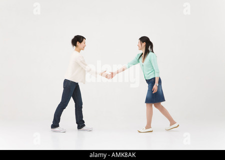 Due giovani donne che si estende handshake Foto Stock
