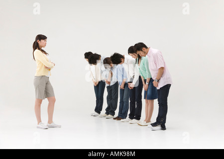 Gruppo di persone che si inchinano a una giovane donna Foto Stock