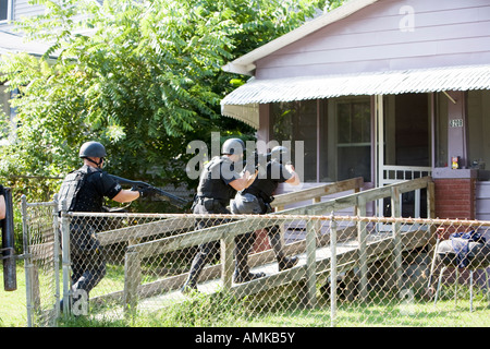 Funzionari di polizia da narcotici tattico di unità che effettua ad alto rischio di un mandato di perquisizione nel sospetto di casa di farmaco. Kansas City SWAT. Foto Stock