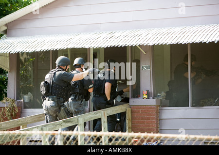 Funzionari di polizia da narcotici tattico di unità che effettua ad alto rischio di un mandato di perquisizione nel sospetto di casa di farmaco. Kansas City SWAT. Foto Stock