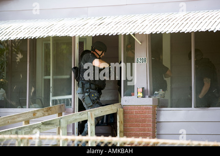 Funzionari di polizia da narcotici tattico di unità che effettua ad alto rischio di un mandato di perquisizione nel sospetto di casa di farmaco. Kansas City SWAT. Foto Stock