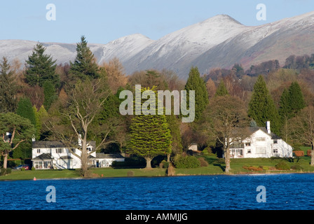 Case con incantevoli giardini in riva al lago di Windermere Near Ambleside con High Street Mountain Range con spruzzi di neve Foto Stock