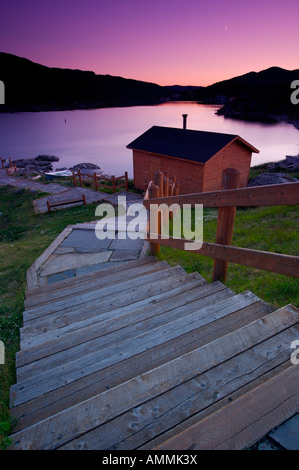 Le fasi che conducono in basso verso un capannone ad un picnic riservare durante il tramonto nella città di Fleur de Lys, Terranova Labrador, Canada. Foto Stock