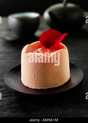 Torta al cioccolato bianco con astuccio in spugna e ripieno di fragole, coperta con polvere di cioccolato bianco rosa e caffè in un tavolo Foto Stock