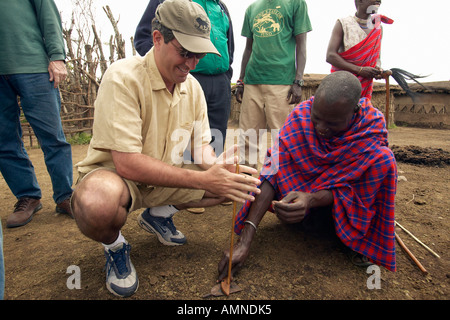 Humane Society Chief Executive Officer Wayne Pacelle imparare a fare fuoco dal tribesman vicino al Parco Nazionale Tsavo in Kenya Foto Stock