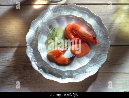 Scampi nel loro guscio con chele di granchio cetriolo e salsa cocktail su bianco pales su legno Foto Stock