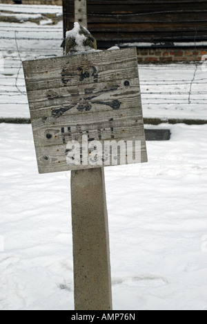 Un segnale di avvertimento (Stop!) davanti a una recinzione di filo spinato al campo di concentramento di Auschwitz 1 (Stammlager), Polonia. Foto Stock