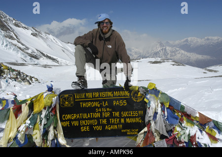 Signor alpinista di successo presso il cartello con le bandiere di preghiera nella neve Thorung La Pass 5416 m Regione Annapurna Nepal Foto Stock