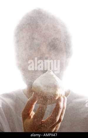 L'uomo, soffiaggio polvere di zucchero da un krapfen, tipica ciambella tedesco Foto Stock