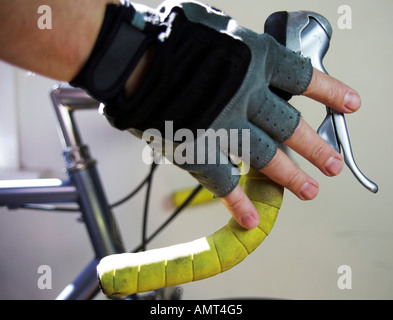 Immagine ravvicinata di ciclisti avambraccio e la mano con i guanti di tenere su strada manubrio della bicicletta e tenendo premuto il freno Foto Stock