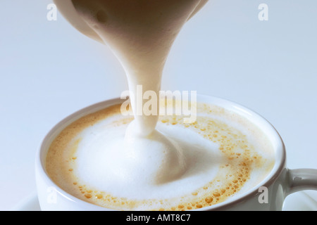 Versare la crema sul Cappuccino Foto Stock