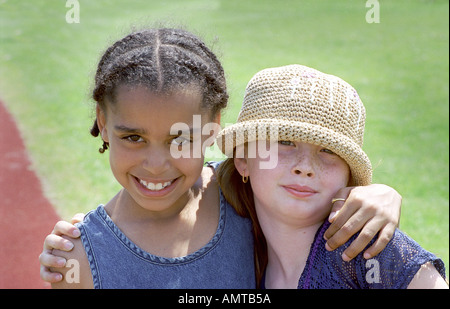 Bianco 7 anno vecchia ragazza con braccio intorno a lei femmina nero amico Foto Stock