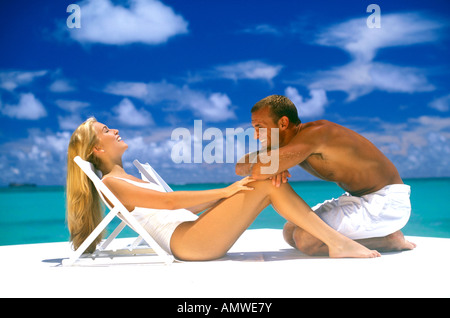 Stati Uniti d'America, isole hawaiane. Coppia felice che indossa tutto bianco relax sulla spiaggia Foto Stock