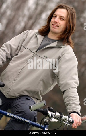 Giovani con i capelli lunghi uomo su una bici Foto Stock