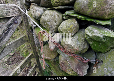 Rusty vecchia catena sul muro di pietra Foto Stock