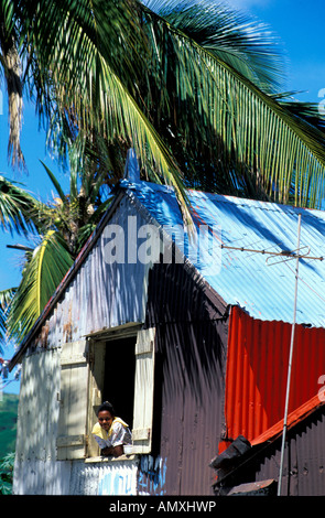 Ritratto di giovane donna che guarda fuori dalla finestra della casa, isola Rodrigues, isola Maurizio Foto Stock