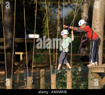 Credito foto DOUG BLANE ragazzo giovane essendo aiutato attraverso un ponte di log all'antenna Extreme Willen Lago di Milton Keynes città di Mil Foto Stock