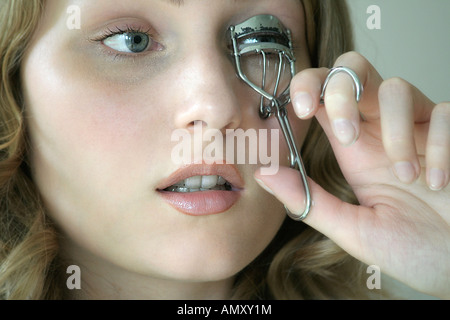 Close-up di giovane donna utilizzando arricciatore ciglia Foto Stock