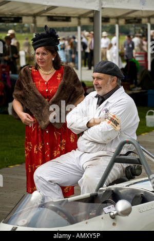 Meccanica e lady amico in attesa nella zona del paddock di Goodwood, Sussex, Regno Unito. Vestito in anni cinquanta costumi. Foto Stock