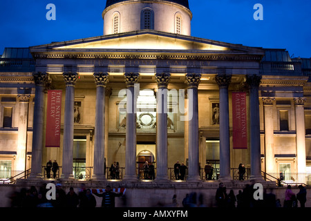 I turisti di fronte all edificio accesa fino al crepuscolo, National Gallery, Trafalgar Square, Westminster, Londra, Inghilterra Foto Stock