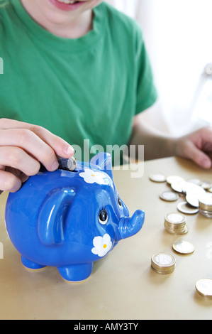 Close-up di boy inserimento di moneta in piggybank Foto Stock