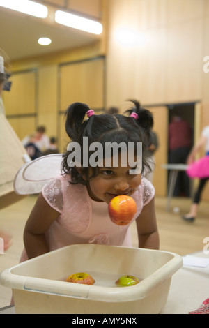 Giovane ragazza vestita come Angelo gode di muovere le mele in alternativa alla notte di Halloween di evento di luce 31 Ottobre Foto Stock